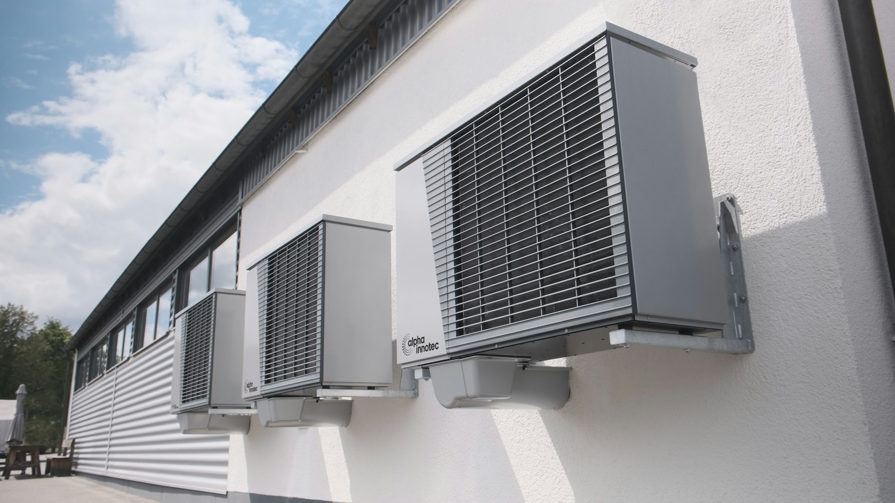 Modern air conditioning units mounted on a white wall under a clear blue sky