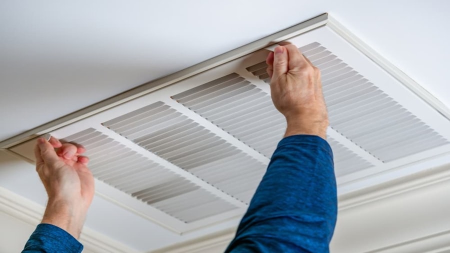 Hands opening a ceiling air conditioning filter grille